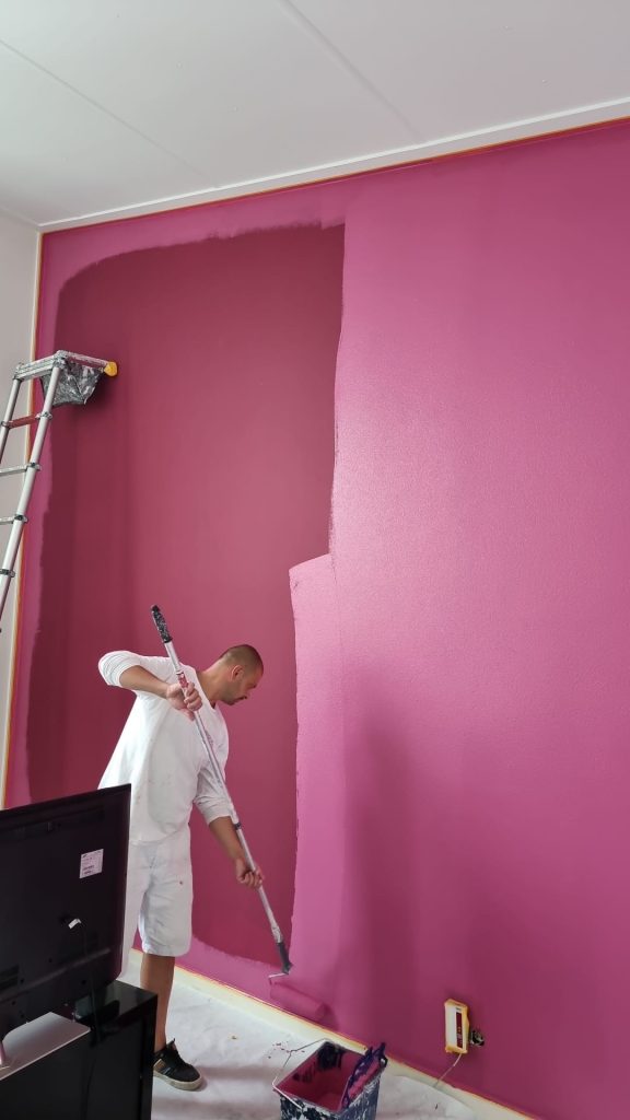 Schilder verft muur roze - professionele muurafwerking en renovatie.