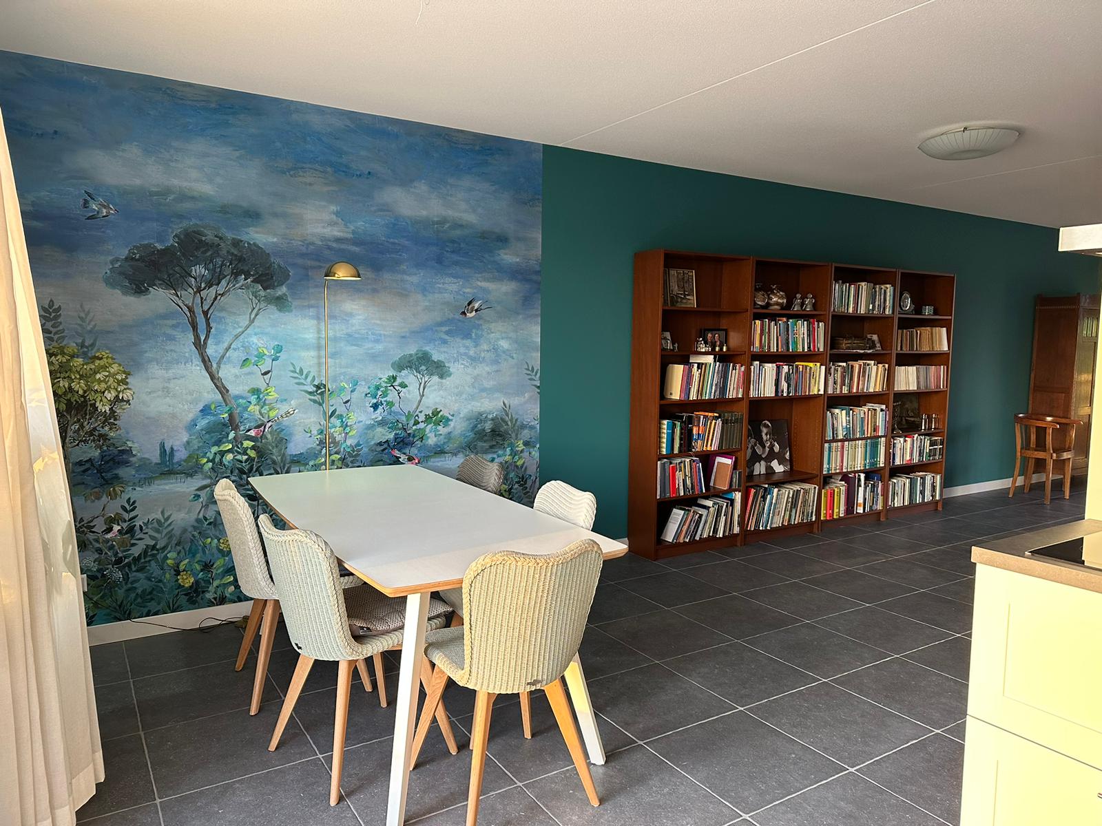 Moderne eetkamer met muurschildering en boekenkast met renovlies